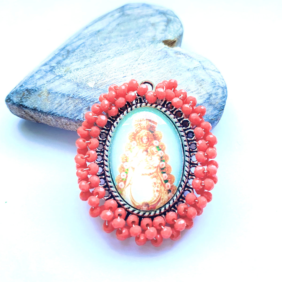 Medalla bordada con cristales coral e imagen de la Virgen sobre un corazón de madera
