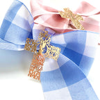 Lazos de cuna de vichy azul y rosa con cruz de oración, de cerca