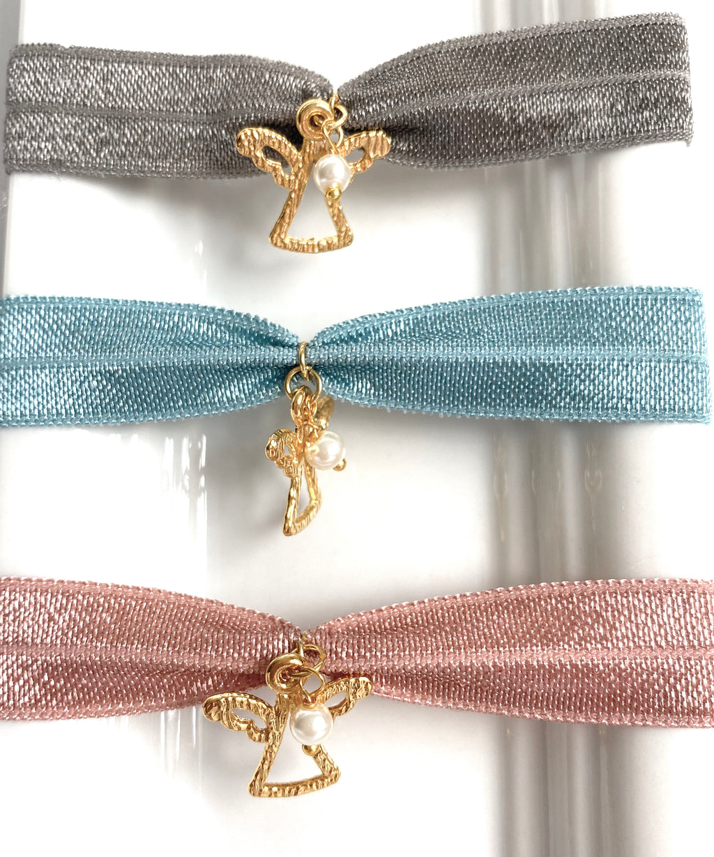 Tres pulseras elásticas con angelito chapado y perlita, de cerca