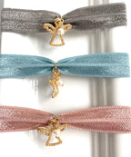 Tres pulseras elásticas con angelito chapado y perlita, de cerca